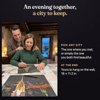 A couple at home on a winter evening: she scratches the Eiffel Tower card while he watches over her shoulder, with a finished New York card on the table. An evening together, a city to keep. Pick any city: the one where you met, or simply the one you both find beautiful. At the end it is yours to hang on the wall, 16 x 11.2 in.