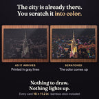 The same New York card twice. As it arrives: the whole city printed in gray lines on black. Scratched: the color comes up. Nothing to draw, nothing lights up. Every card 16 x 11.2 in, bamboo stick included.