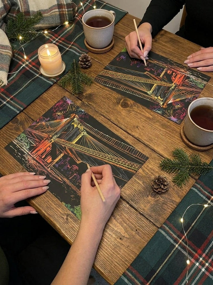 Two people scratching the same city across a wooden table, with tea and candles